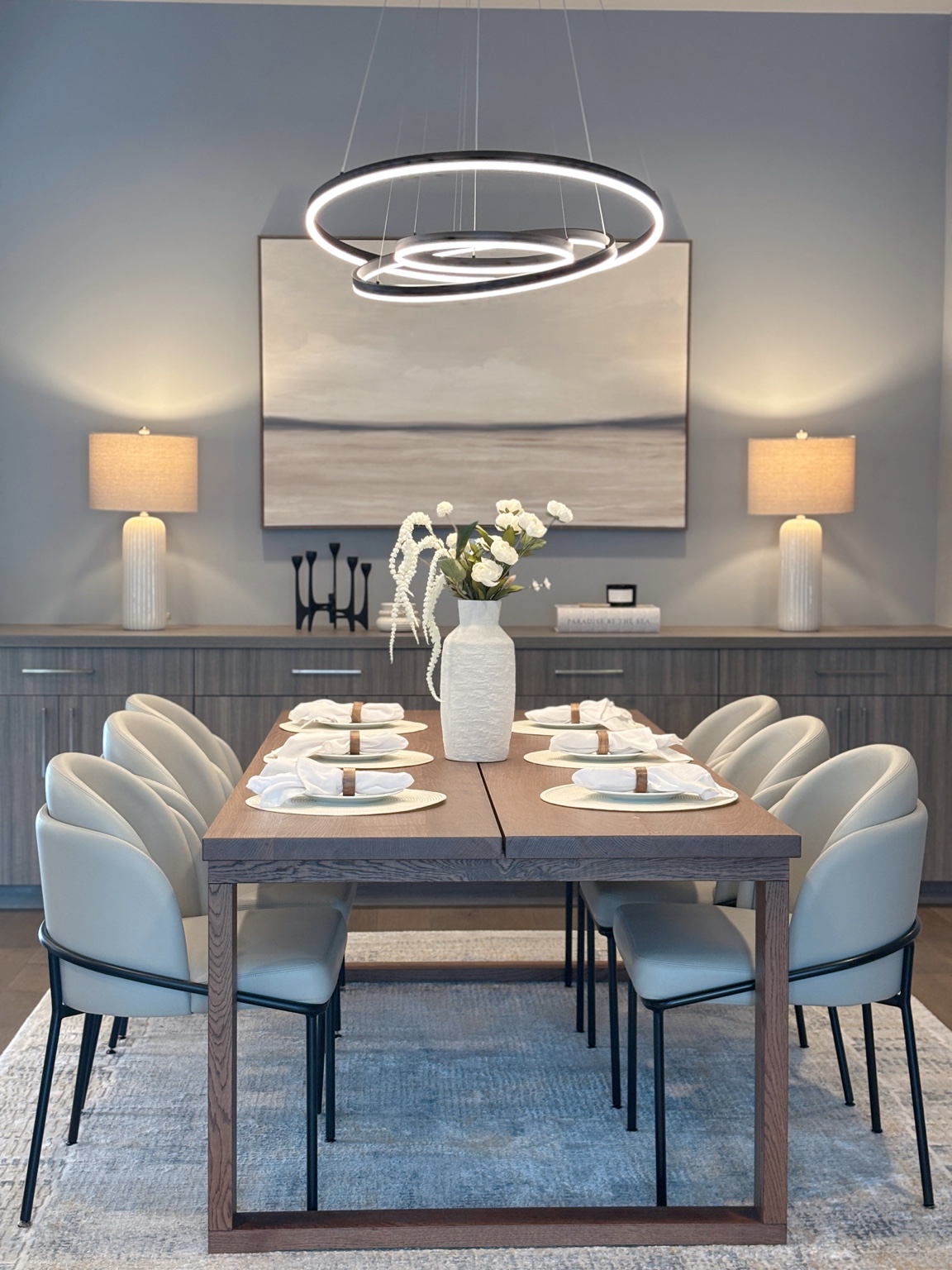 Dining room with blue chairs and sculptural ring chandelier