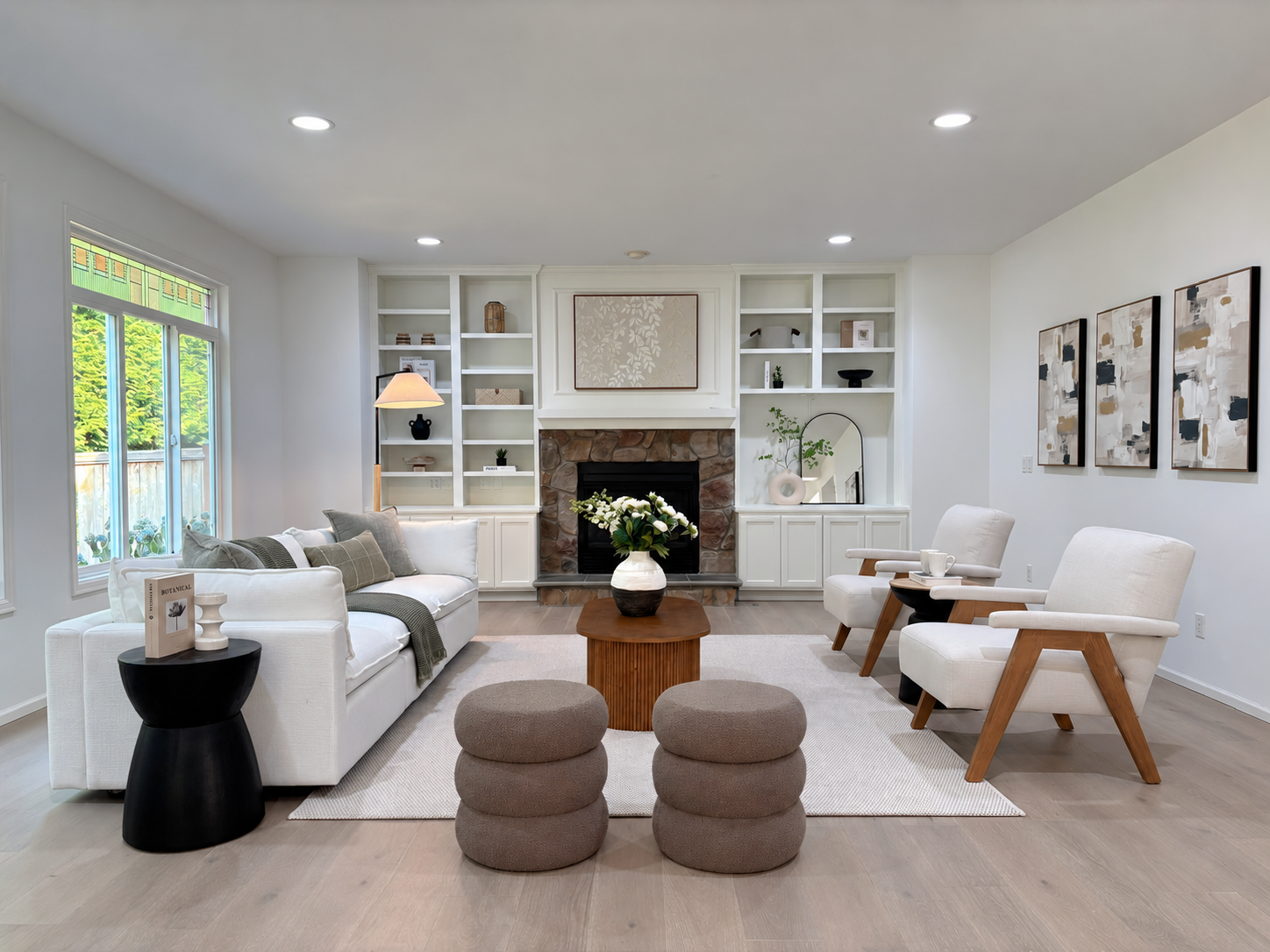 Bright staged living room with stone fireplace and soft white seating