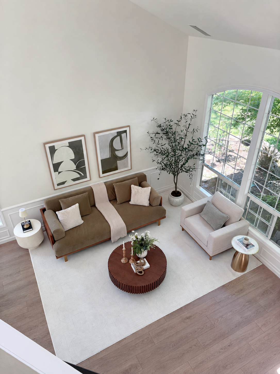 Staged living room with olive sofa, round wood table, and layered accessories